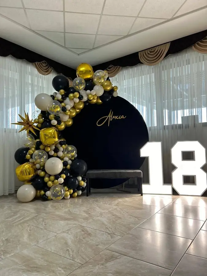 Arcadă de baloane negru cu auriu și cifra 18 luminoasă, la un majorat